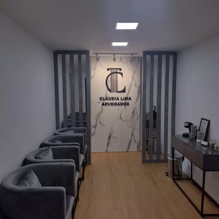 Recepção do escritório Claudia Lima Advogados em Londrina, com poltronas cinzas e a logo em parede de mármore